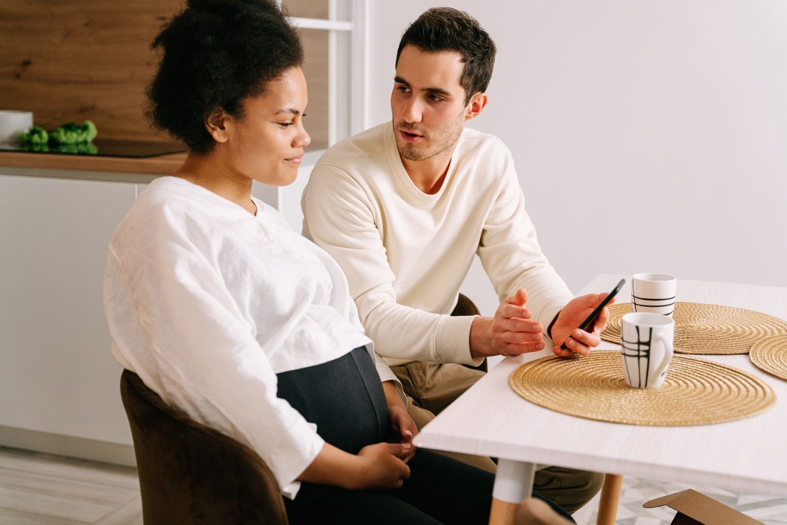 An expectant couple talking through plans together at the kitchen table