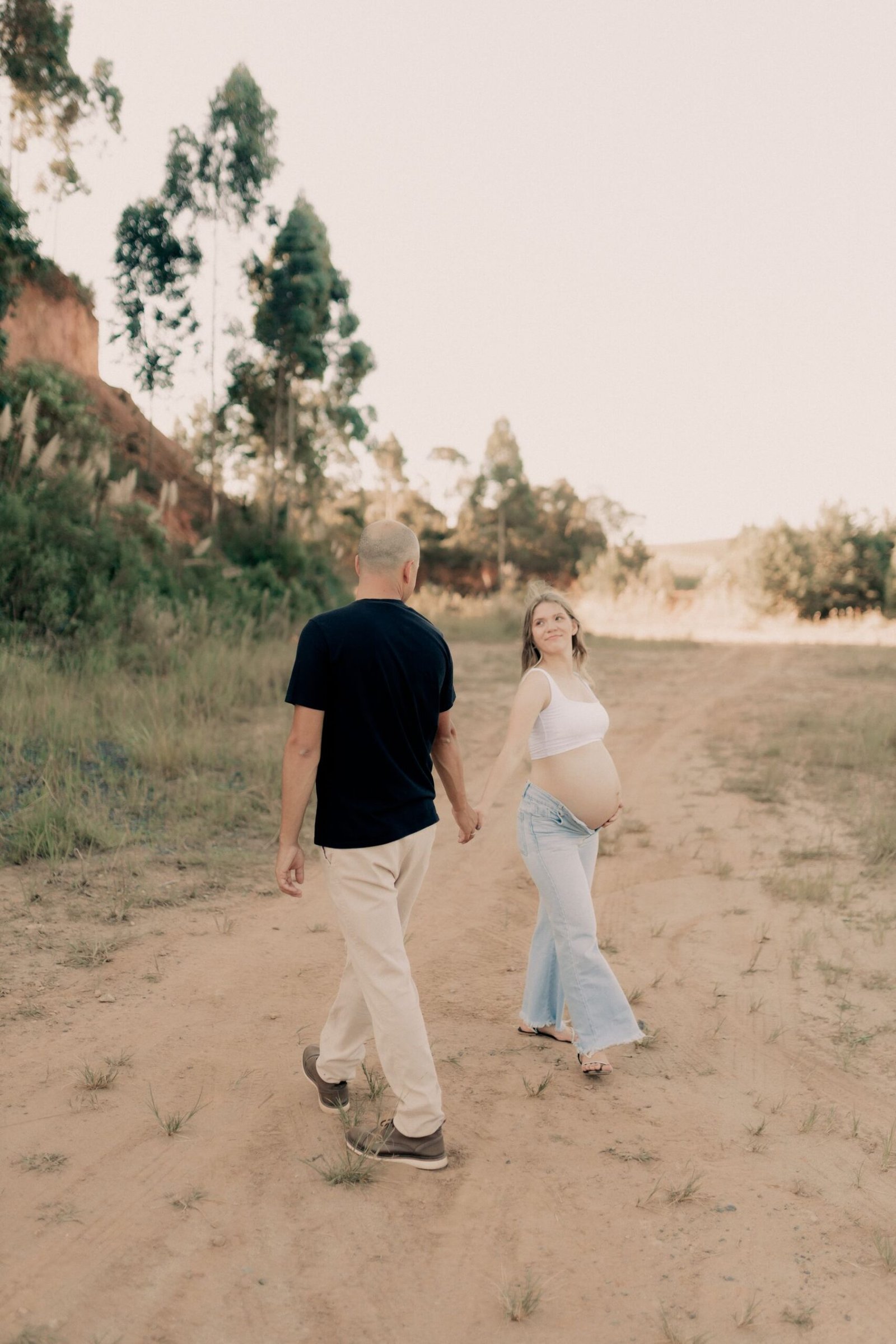 An expectant couple taking a gentle walk together on a sunny path